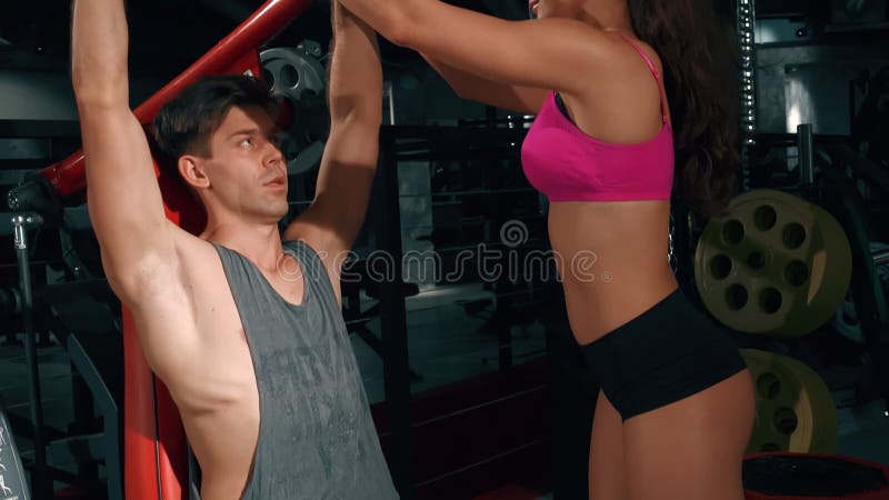 Assistance mutuelle et aide dans les sports et la remise en forme. jeune fille aide le gars pomper les muscles des bras sur l'entr banque de vidéos