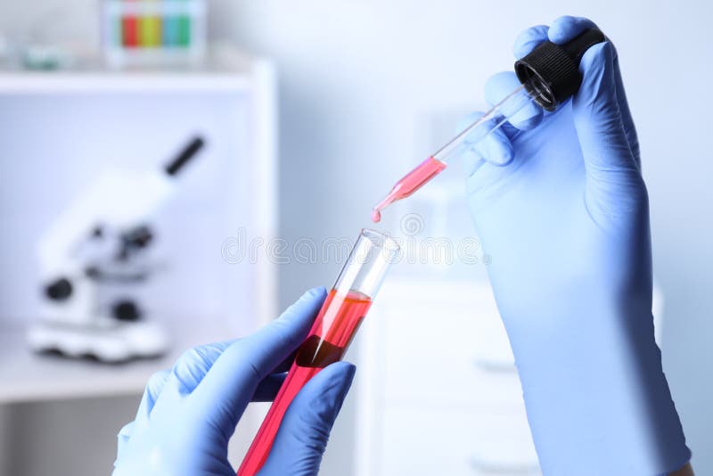 Assistant dripping sample into test tube at chemistry laboratory stock photos Assistant dripping sample into test tube at chemistry laboratory stock photos