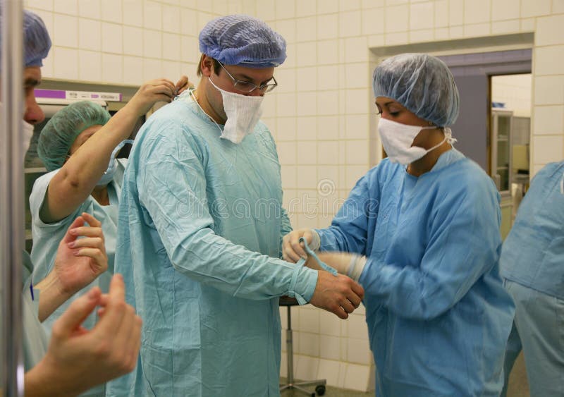 Assistants dress the surgeon b stock image Assistants dress the surgeon b stock image