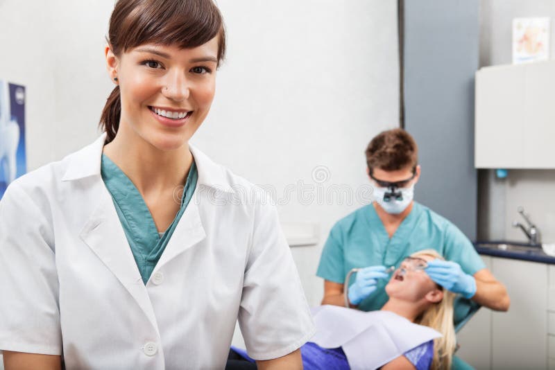 Assistente con l'attività di odontoiatria nei precedenti fotografie stock libere da diritti Assistente con l'attività di odontoiatria nei precedenti fotografie stock libere da diritti