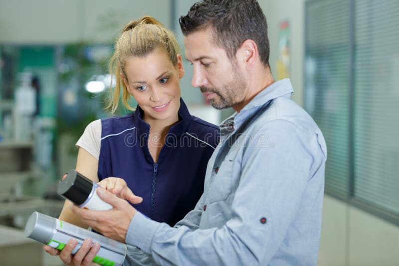 Assistente de vendas avisando o cliente na loja de hardware imagens de stock royalty free