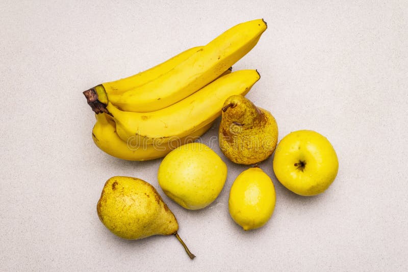 Assorted bright yellow fruits. Fresh banana, pear, apple, lemon. Harvest on a stone background royalty free stock photo Assorted bright yellow fruits. Fresh banana, pear, apple, lemon. Harvest on a stone background royalty free stock photo