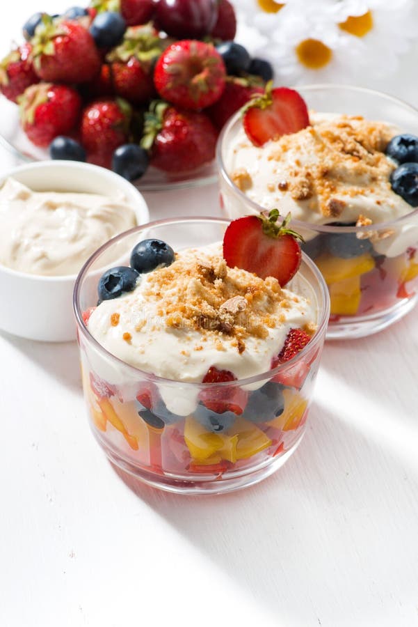 Assorted fresh fruit with custard on white table, vertical