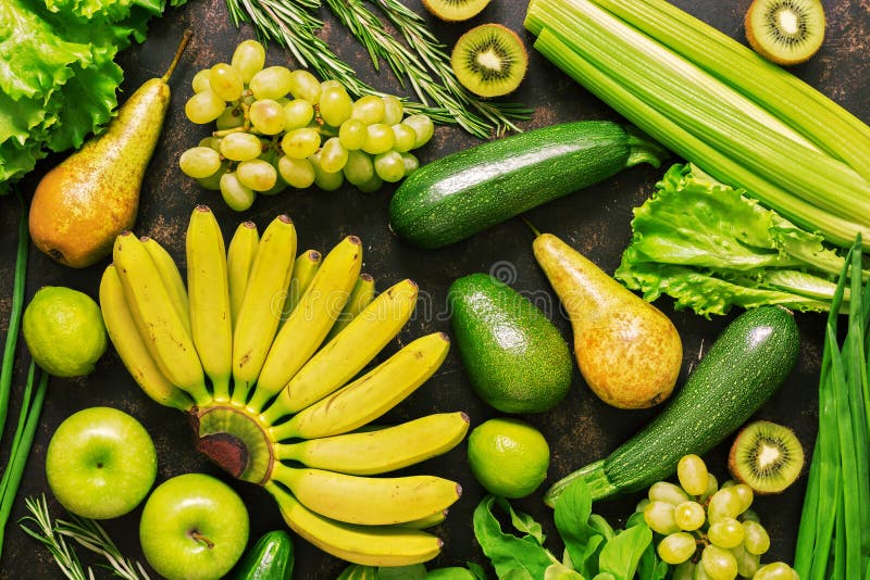 Assorted fresh vegetables and fruits of green, yellow color on a dark background. Top view, flat lay