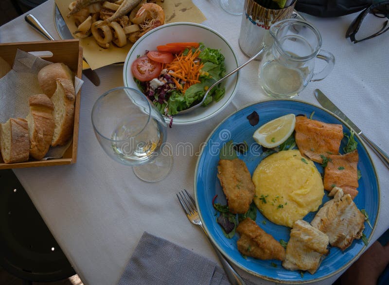 Assorted Fried Fish with Polenta Mixed Salad and Bread on a Blue Plate