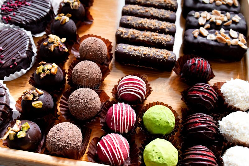 Assorted gourmet chocolate truffles with nuts and toppings on display stock photos