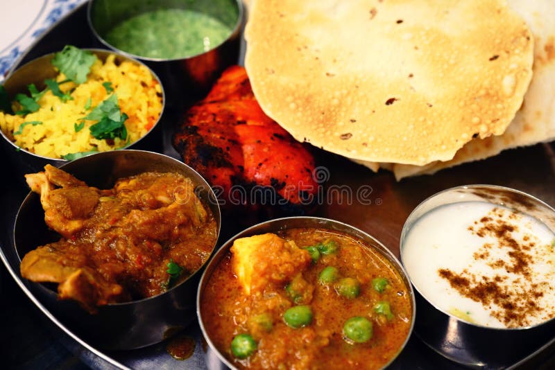 Assorted Indian food set in tray for dinner, tanduri chicken, naan bread, yoghurt, traditional curry, roti