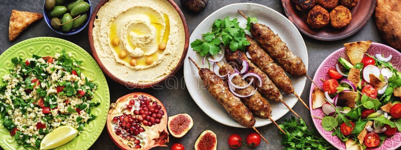 Assorted Middle Eastern and arabic dishes on a dark rustic background,border. Hummus,tabbouleh, salad Fattoush,pita,meat kebab