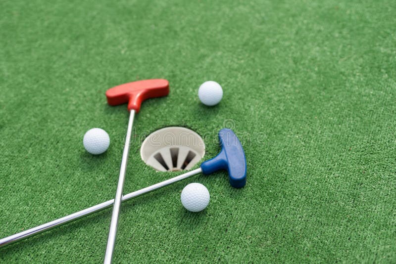 Assorted Miniature Golf Putters and Balls Askew on Synthetic Grass