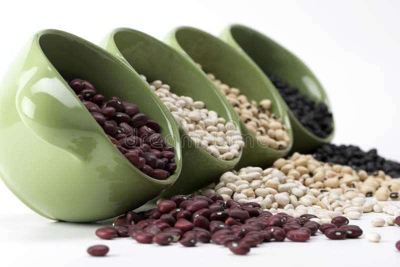 Assorted variety of mixed dried beans spilling from a green ceramic dish. Assorted variety of mixed dried beans spilling from a green ceramic dish