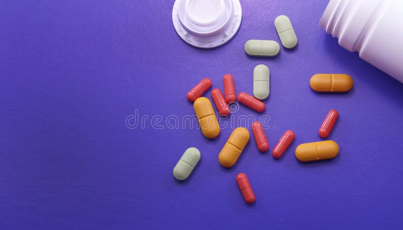 Assorted pharmaceutical medicine pills, tablets and capsules. Pills on purple background.