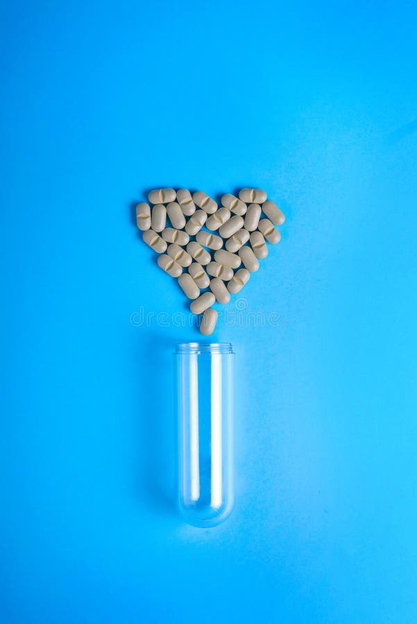 Pharmaceutical medicine pills, tablets and capsules for treatment of heart disease. Heart shape and bottle of pills.