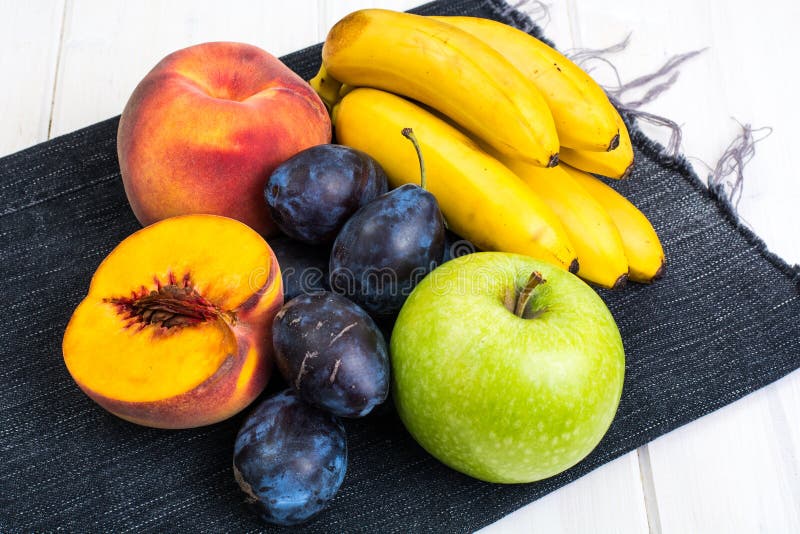 Assorted Ripe Fresh Plums, Bananas, Peaches And Apples On White Table