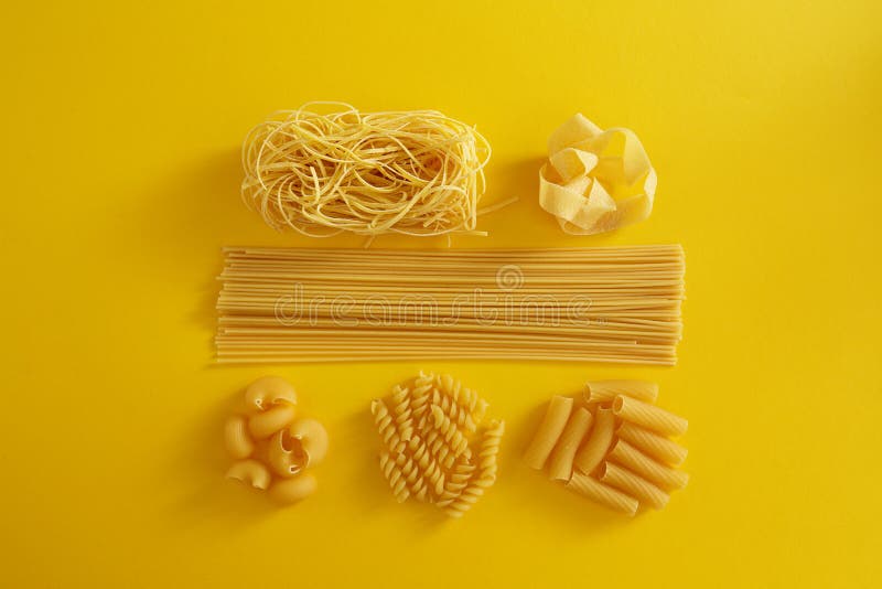 Assorted types of pasta on yellow background. stock image