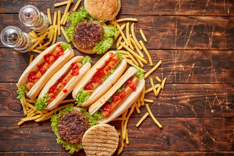 Assortiment de prêt-à-manger Hamburgers et hot-dogs placés sur la table en bois rouillée photographie stock libre de droits Assortiment de prêt-à-manger Hamburgers et hot-dogs placés sur la table en bois rouillée photographie stock libre de droits