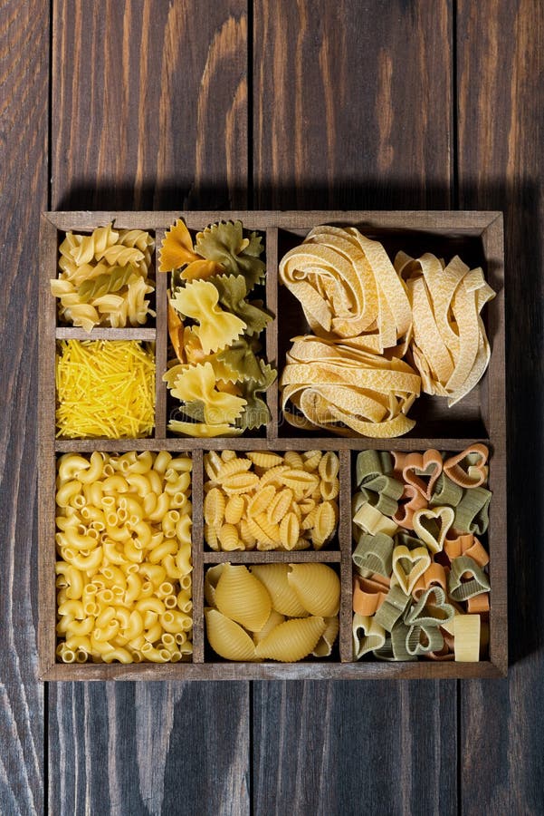 Assortiment des pâtes sèches dans une boîte en bois, vue supérieure verticale image libre de droits Assortiment des pâtes sèches dans une boîte en bois, vue supérieure verticale image libre de droits