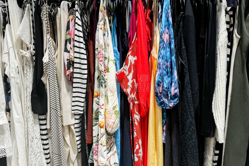 Assortimento colorato di vari capi di abbigliamento appesi su un rack in un negozio fotografie stock