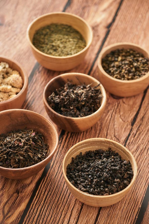 Assortment of Dry Tea in White Bowls on Wooden Surface Stock Image
