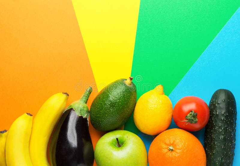 Assortment of fresh raw ripe seasonal fruits vegetables on multicolored pinwheel background. Creative food poster. Vitamins health