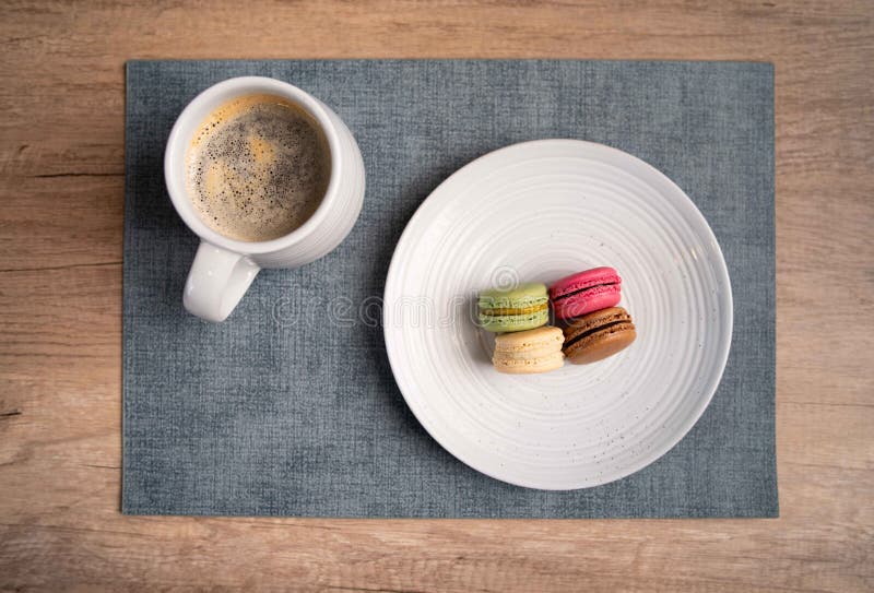 Assortment of macaroons with different colors accompanied with a nice coffee in mug at a french bistro royalty free stock photo