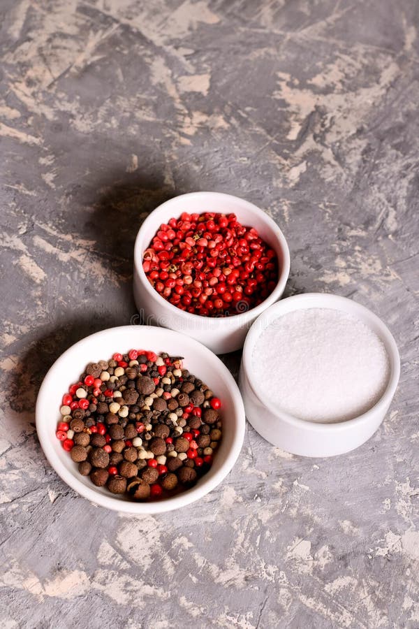 Assortment of Pepper and Salt in Bowls, Closeup, Vertical Stock Photo