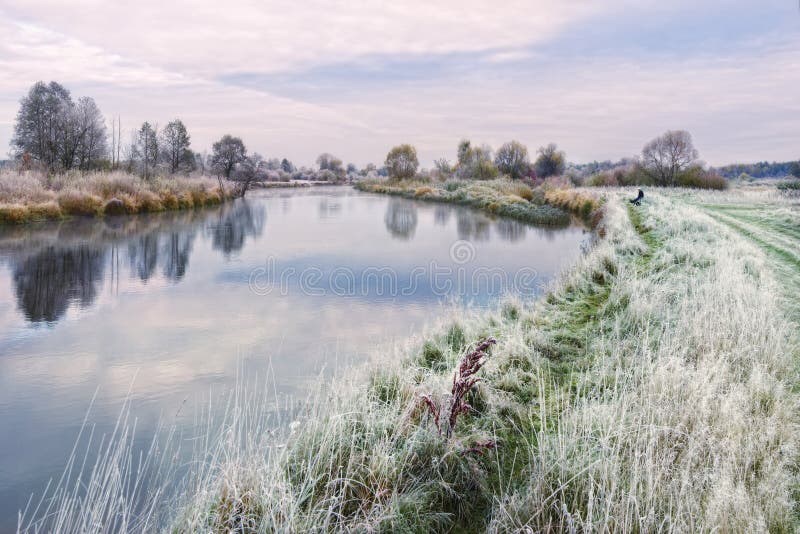 Assunto bonito de Autumn Belarusian Landscape On The da pesca: Banco gramíneo de Sits On The do pescador solitário do rio, cobert imagem de stock Assunto bonito de Autumn Belarusian Landscape On The da pesca: Banco gramíneo de Sits On The do pescador solitário do rio, cobert imagem de stock