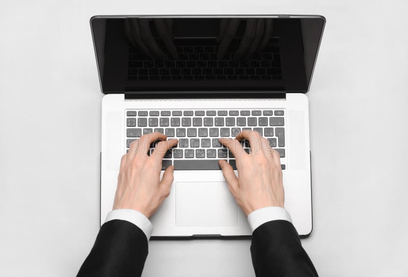 Assunto do negócio e da tecnologia: a mão do homem em um terno preto que mostra o gesto contra um portátil cinzento e branco do f foto de stock royalty free Assunto do negócio e da tecnologia: a mão do homem em um terno preto que mostra o gesto contra um portátil cinzento e branco do f foto de stock royalty free