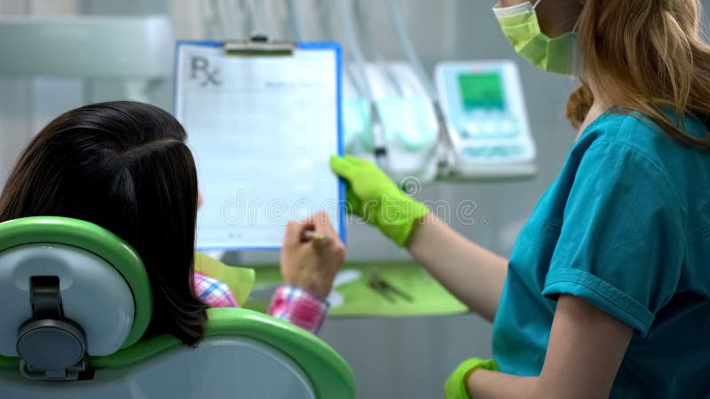 Assurance de signature de Madame avant la chirurgie dentaire ou le traitement, prescriptions de santé photographie stock Assurance de signature de Madame avant la chirurgie dentaire ou le traitement, prescriptions de santé photographie stock