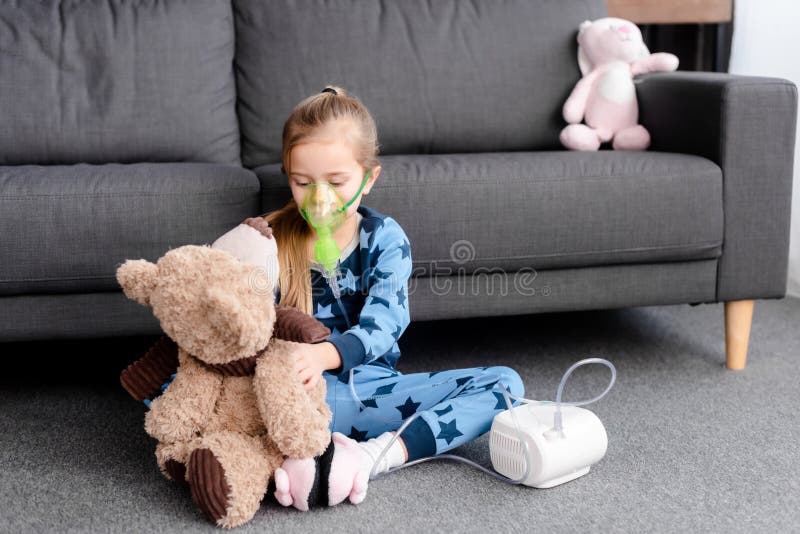 Child using compressor inhaler and holding royalty free stock photography