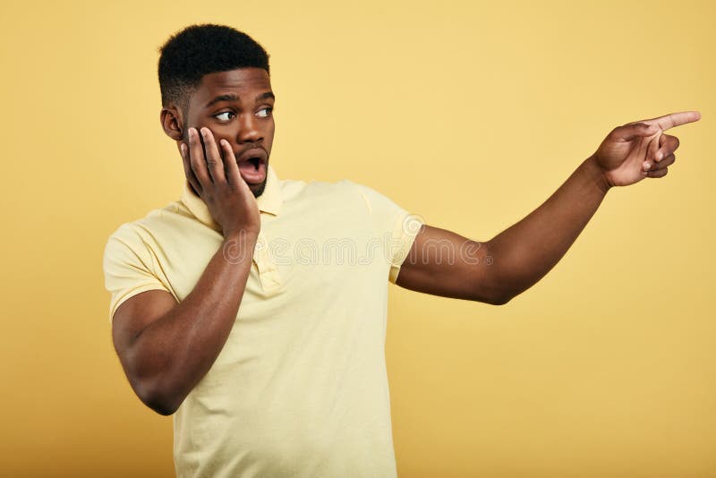 Astonished emotional young dark-skinned man dressed in stylish T-shirt stock photo Astonished emotional young dark-skinned man dressed in stylish T-shirt stock photo