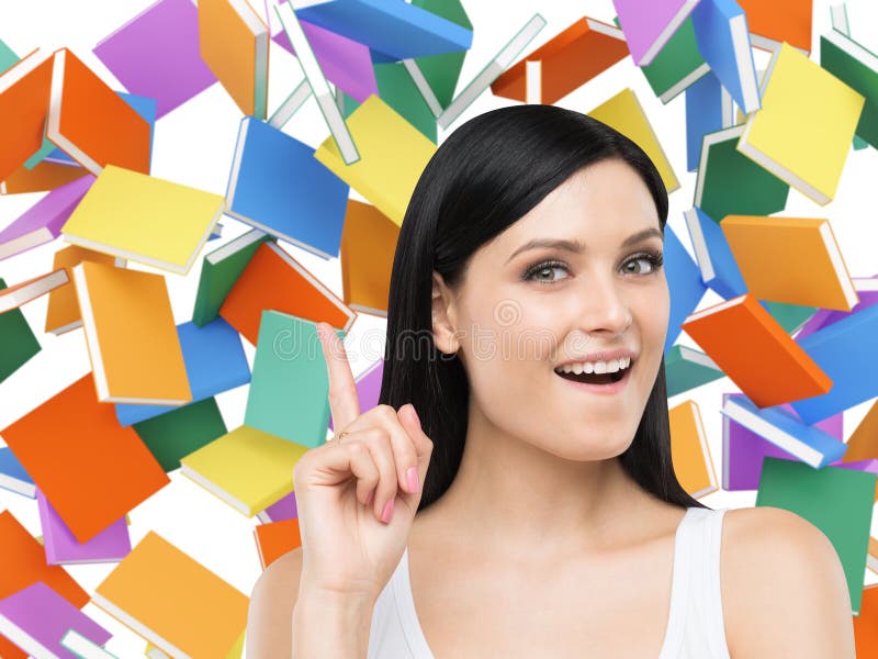 Astonishing girl is thinking about education and pointing out her finger up. Colourful books on the background.