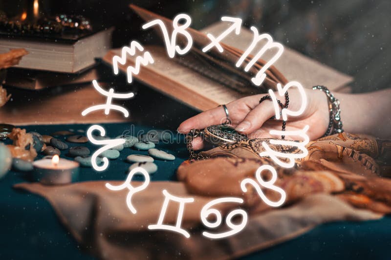 Astrologia ed esoterismo La mano femminile della strega tiene in mano un amuleto In fondo, vecchi libri, fortuna... fotografia stock libera da diritti Astrologia ed esoterismo La mano femminile della strega tiene in mano un amuleto In fondo, vecchi libri, fortuna... fotografia stock libera da diritti