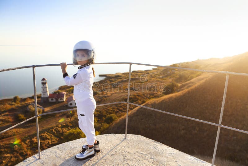 Astronaut futuristic kid girl with white full length uniform and helmet wearing silver shoes outdoors stock photography Astronaut futuristic kid girl with white full length uniform and helmet wearing silver shoes outdoors stock photography