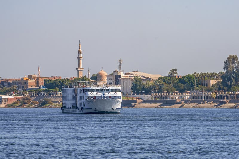 12 11 2018 Aswan, Egypten, en enorm kryssningfärja som fortskrider en nile mot bakgrunden av en stad arkivfoto 12 11 2018 Aswan, Egypten, en enorm kryssningfärja som fortskrider en nile mot bakgrunden av en stad arkivfoto