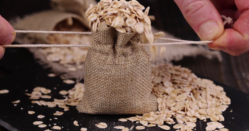 Atar una bolsa de lino gruesa con gotas de avena almacen de metraje de vídeo