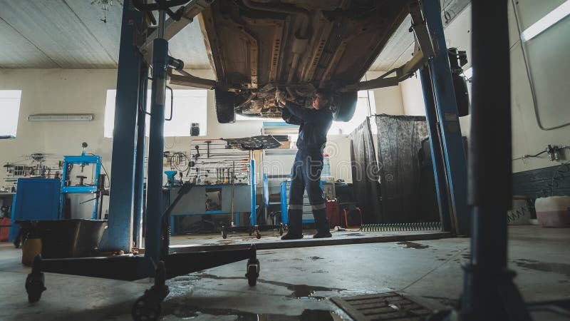 Atelier mécanique de garage - le mécanicien vérifie le fond de la position automatique soulevée automobile dans le service d'auto image libre de droits Atelier mécanique de garage - le mécanicien vérifie le fond de la position automatique soulevée automobile dans le service d'auto image libre de droits