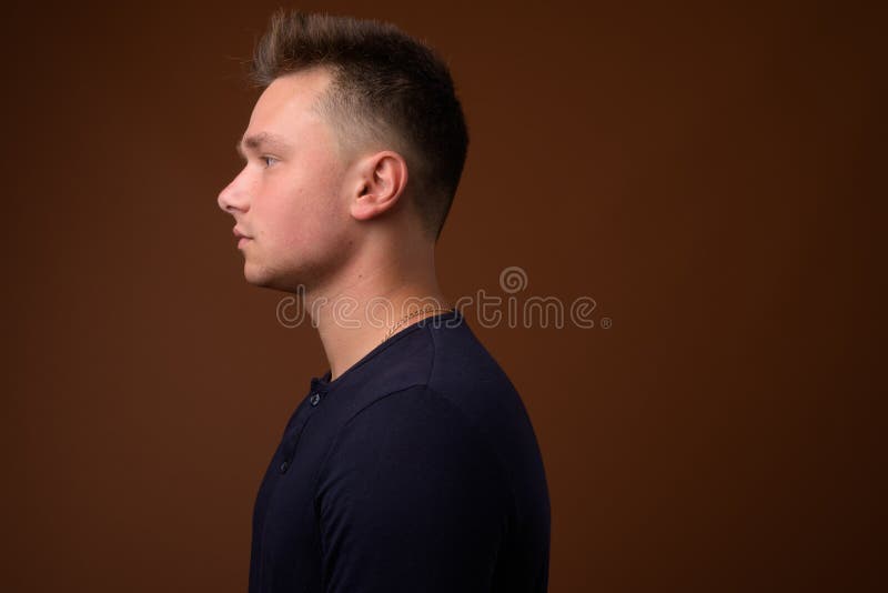 Atelieraufnahme des jungen gut aussehenden Mannes gegen braunen Hintergrund lizenzfreie stockfotos Atelieraufnahme des jungen gut aussehenden Mannes gegen braunen Hintergrund lizenzfreie stockfotos