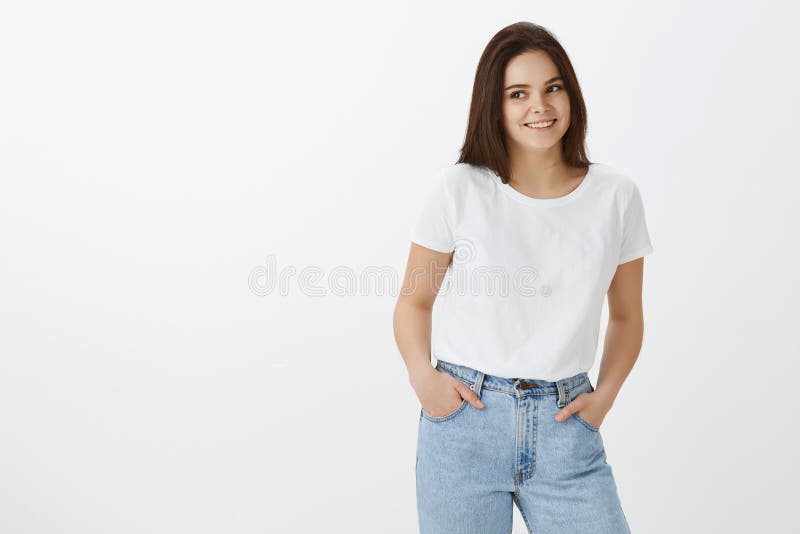 Atelieraufnahme des stilvollen weiblichen städtischen Mädchens mit dem dunklen Haar in den modischen Jeans und im T-Shirt, Händch stockfoto Atelieraufnahme des stilvollen weiblichen städtischen Mädchens mit dem dunklen Haar in den modischen Jeans und im T-Shirt, Händch stockfoto
