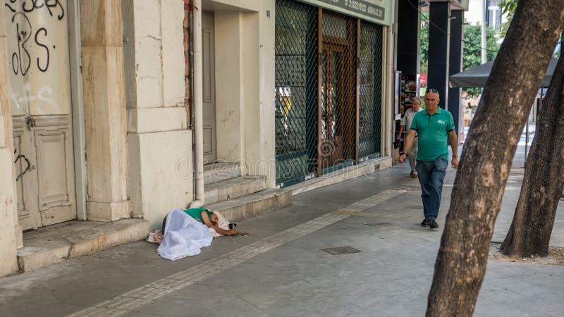 Aten Grekland-Augusti 17, 2018: Hemlös man som sover på trottoaren royaltyfria bilder Aten Grekland-Augusti 17, 2018: Hemlös man som sover på trottoaren royaltyfria bilder