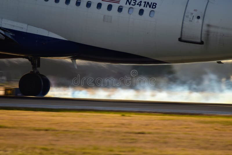 Aterrissagem de avião de Delta Airlines em uma pista de decolagem com fumo do pneu foto de stock Aterrissagem de avião de Delta Airlines em uma pista de decolagem com fumo do pneu foto de stock