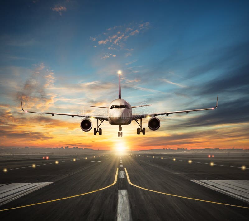 Aterrissagem de avião à pista de decolagem do aeroporto na luz do por do sol foto de stock Aterrissagem de avião à pista de decolagem do aeroporto na luz do por do sol foto de stock