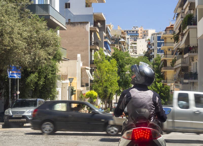 Athens, Greece. August 2019: a Motorcyclist in gear and helmet stopped at a traffic light on a street in the center of the Greek c royalty free stock image Athens, Greece. August 2019: a Motorcyclist in gear and helmet stopped at a traffic light on a street in the center of the Greek c royalty free stock image