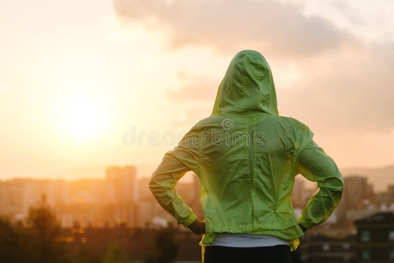 Athlete looking sunset over city skyline after exercising