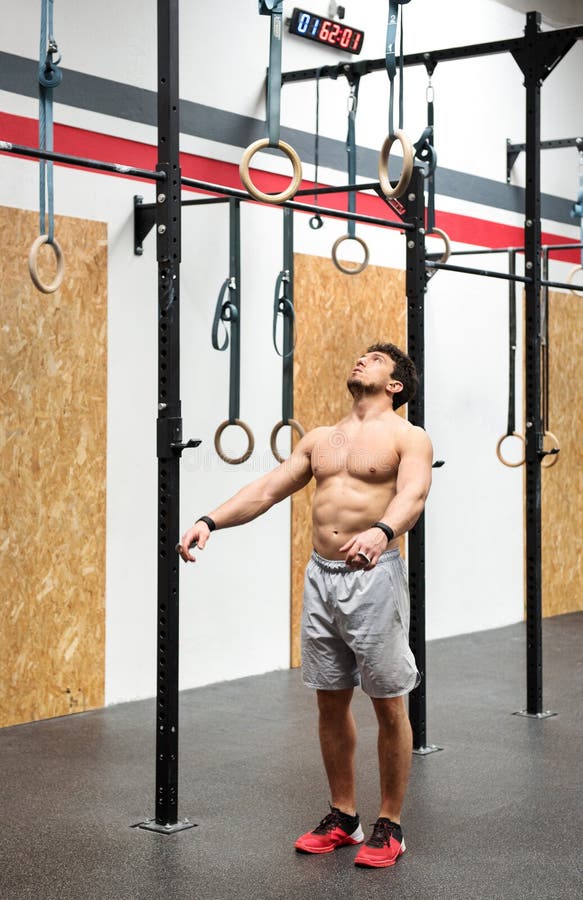 Muscular fit young male athlete psyching himself up to workout on steady rings looking up and focusing his mind on the equipment in a gym. Muscular fit young male athlete psyching himself up to workout on steady rings looking up and focusing his mind on the equipment in a gym