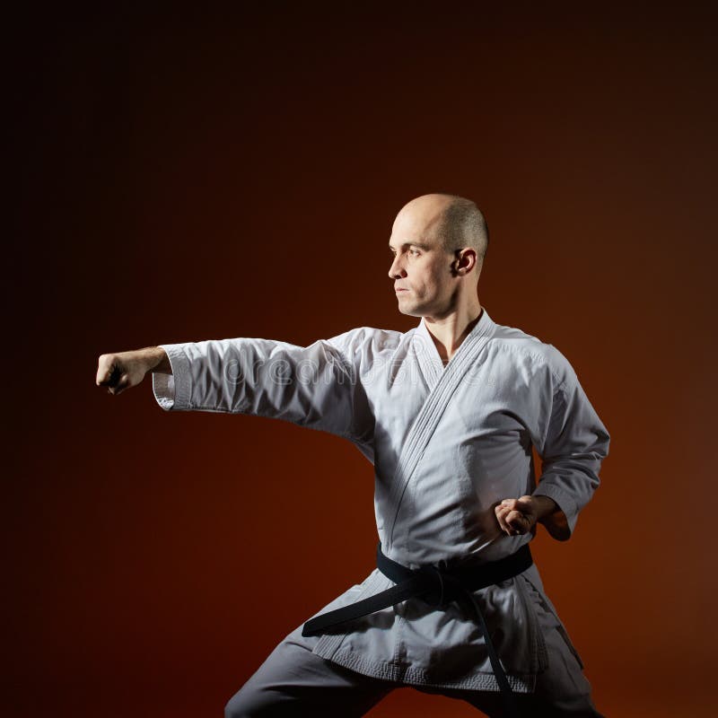 Athlete Trains Formal Karate Exercises Against a Burgundy Background ...