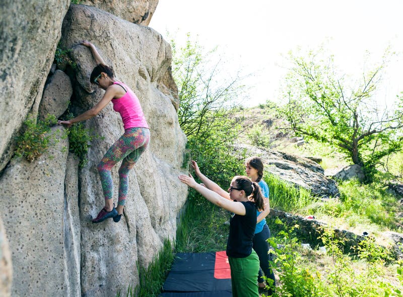 Athletes are bouldering outdoors.