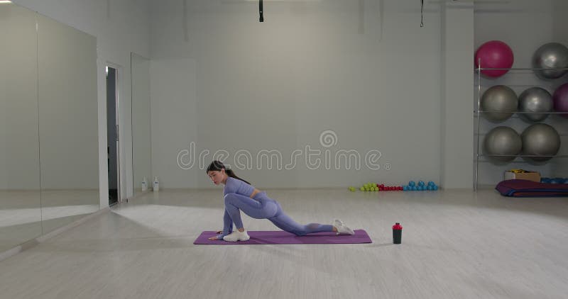 Athletic girl en train de faire de l'avant-midi s'étire dans un cadre moderne de gym pendant une séance de fitness clips vidéos