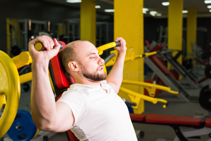 Athletic Male Doing Workouts with Power Exercise Machine in a Gym Club