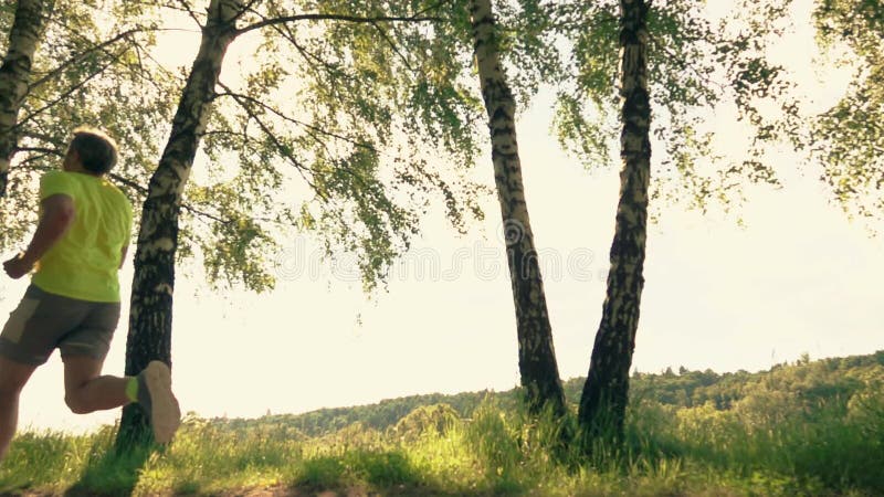 Athletic man running along the park alley