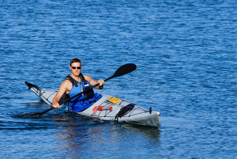 Athletic man showing off in sea kayak